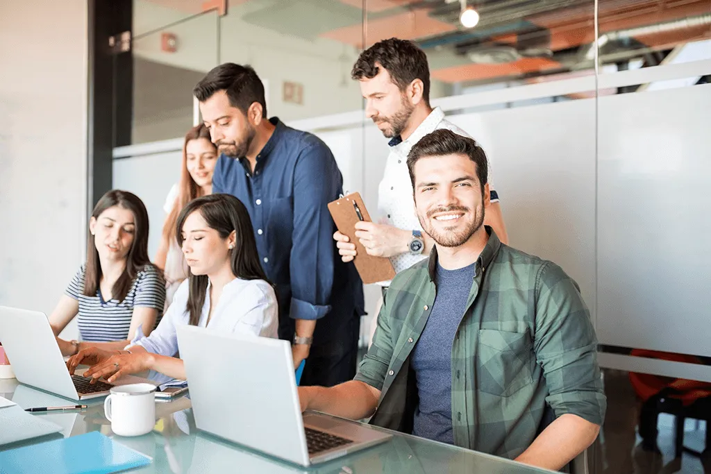portrait-handsome-latin-man-casuals-sitting-with-colleagues-working-back Happy workers efficiently using NetSuite