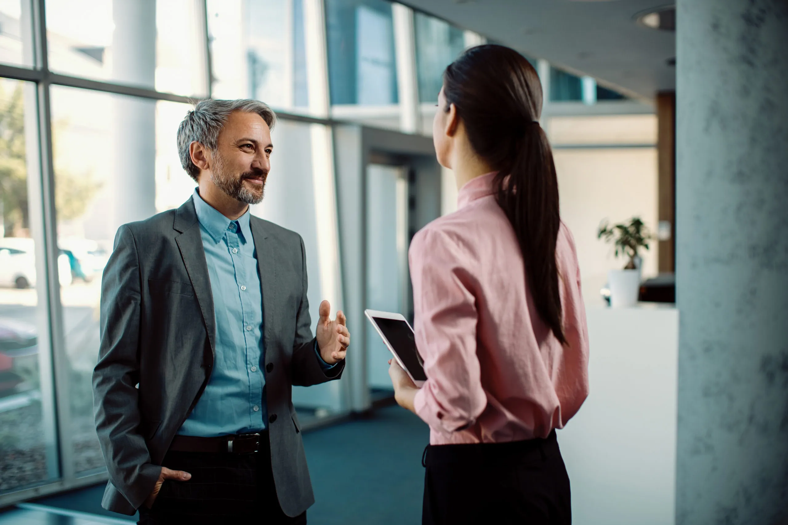 Happy businessman talking to his female colleague in a hallway.